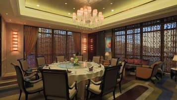 A dining area with a round table, chairs, and a chandelier.