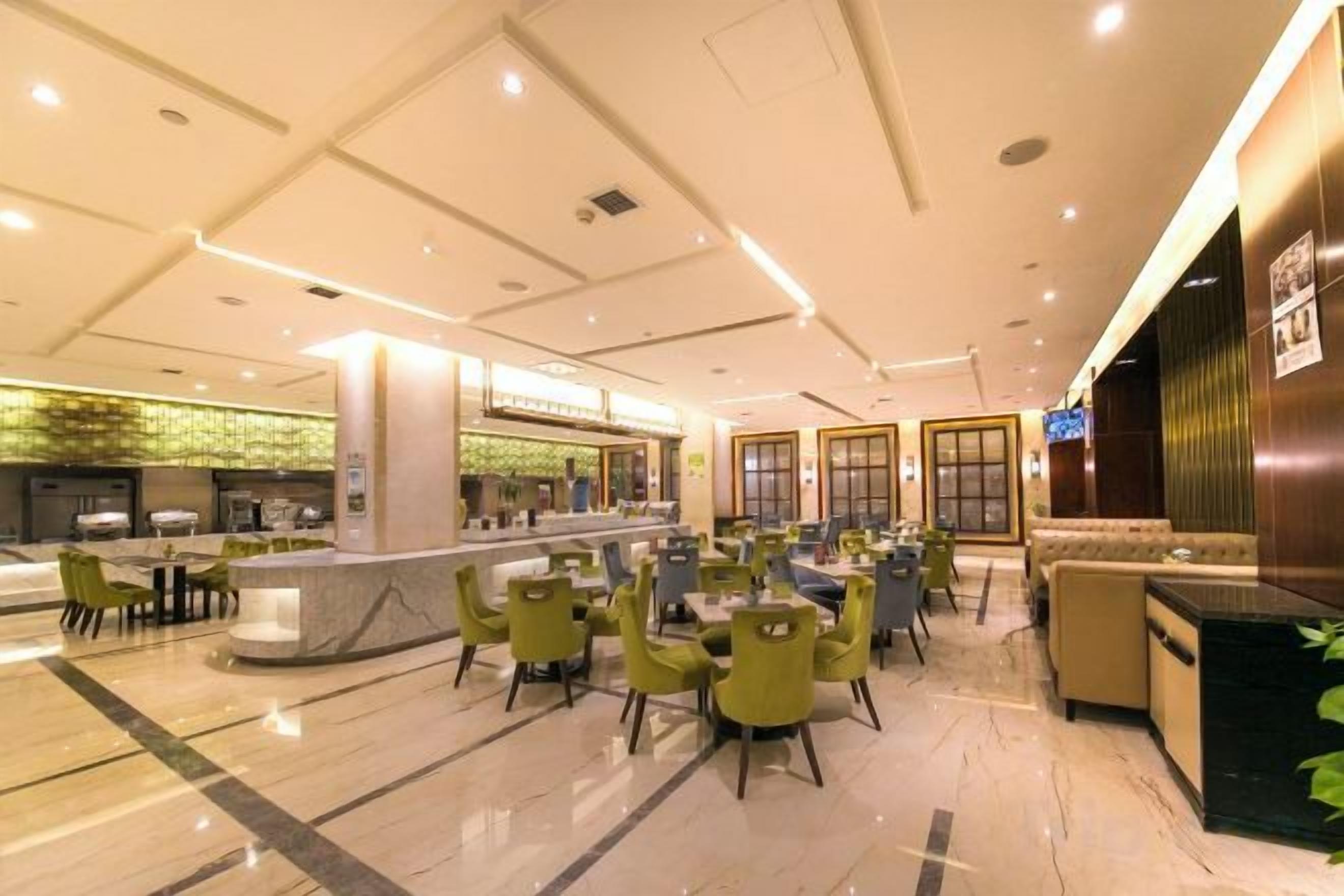A spacious lobby with a reception desk, seating area, and a counter with a green mosaic backsplash.