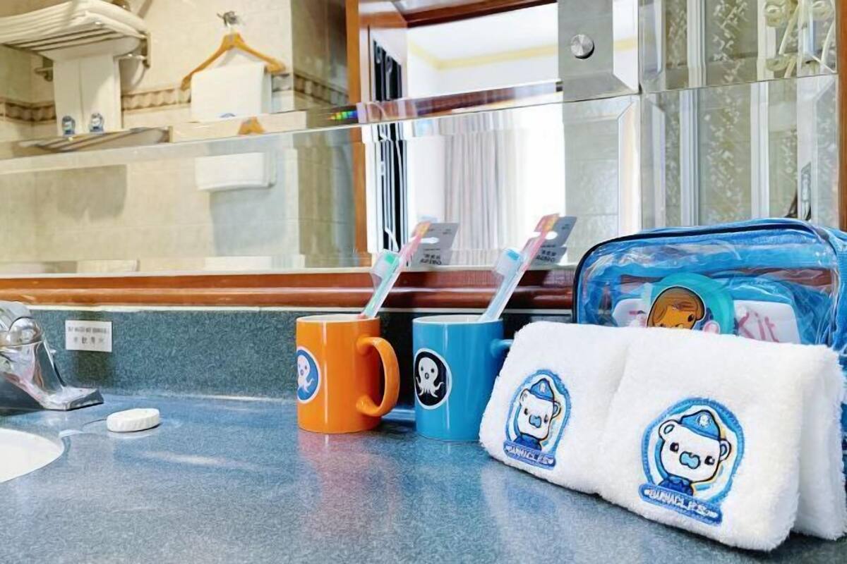 A bathroom counter with a towel, a mug, and a bag with a bear design.