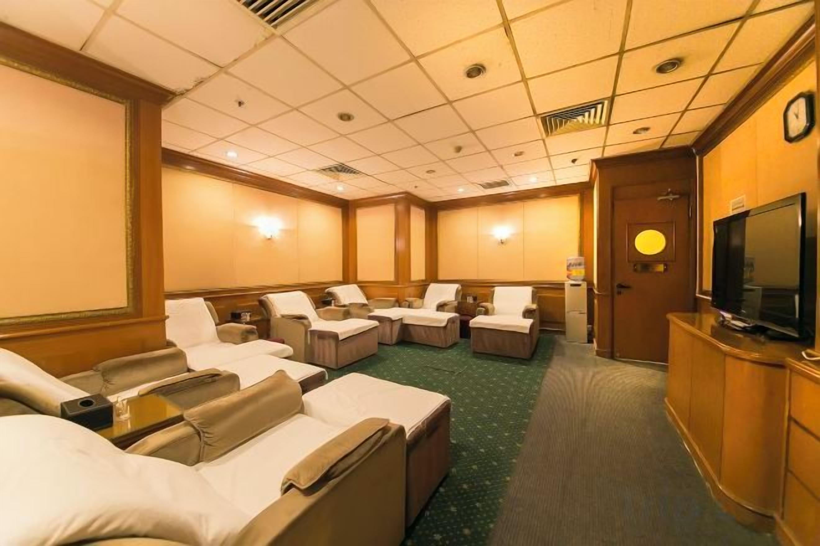 Habitación de hotel con varias zonas de estar, televisor y mostrador de recepción.