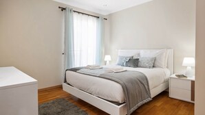 A bedroom with a bed, bedside tables, a nightstand, a window with curtains, and a wooden floor. - Penthouse Prestige by Homie (Funchal)