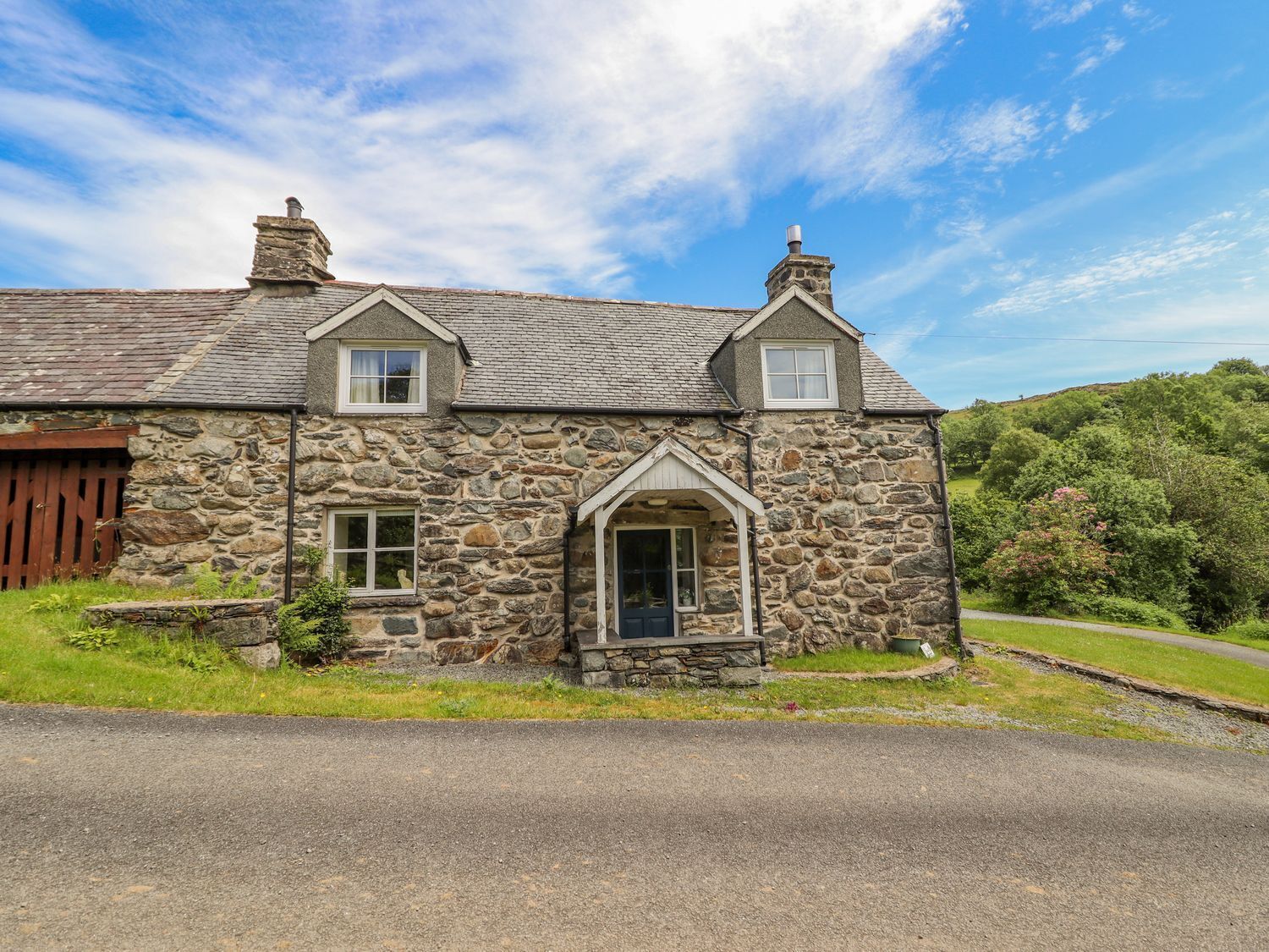 A stone house with a gabled roof, a small porch, and a wooden door.