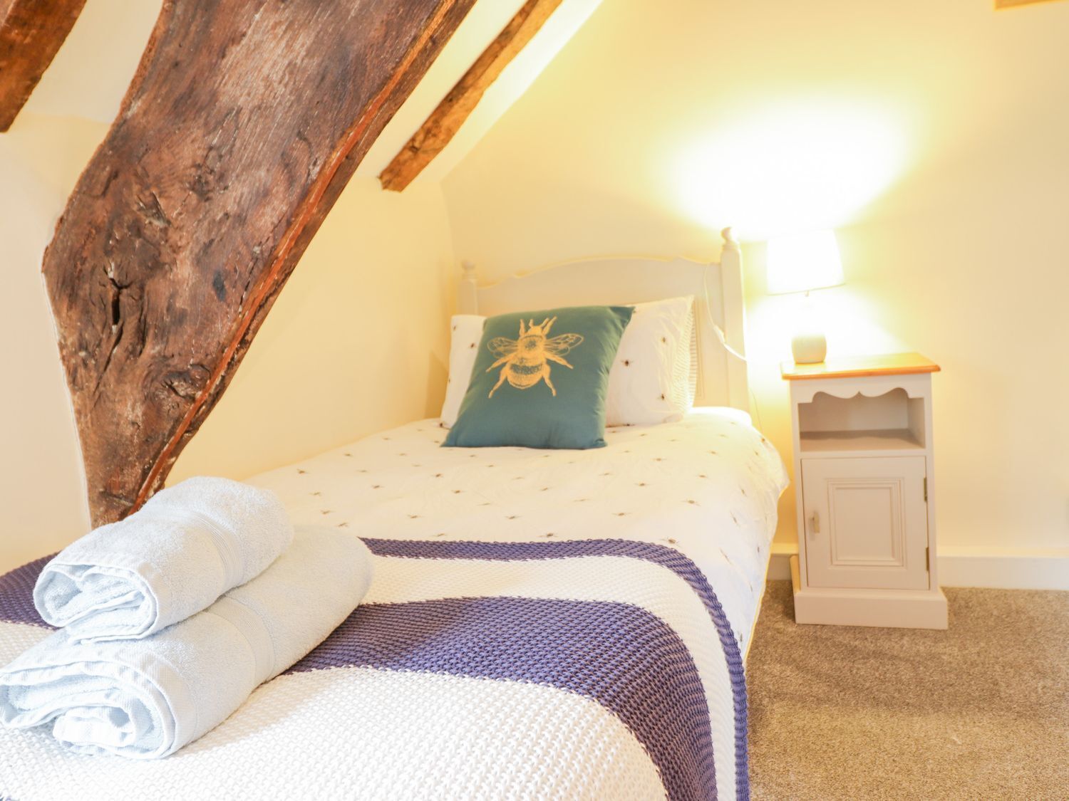 Un dormitorio acogedor con cama, almohadas, mesita de noche y lámpara.