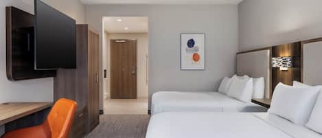 A hotel room with two beds, a desk, a chair, a flat-screen TV, and a door leading to another room.