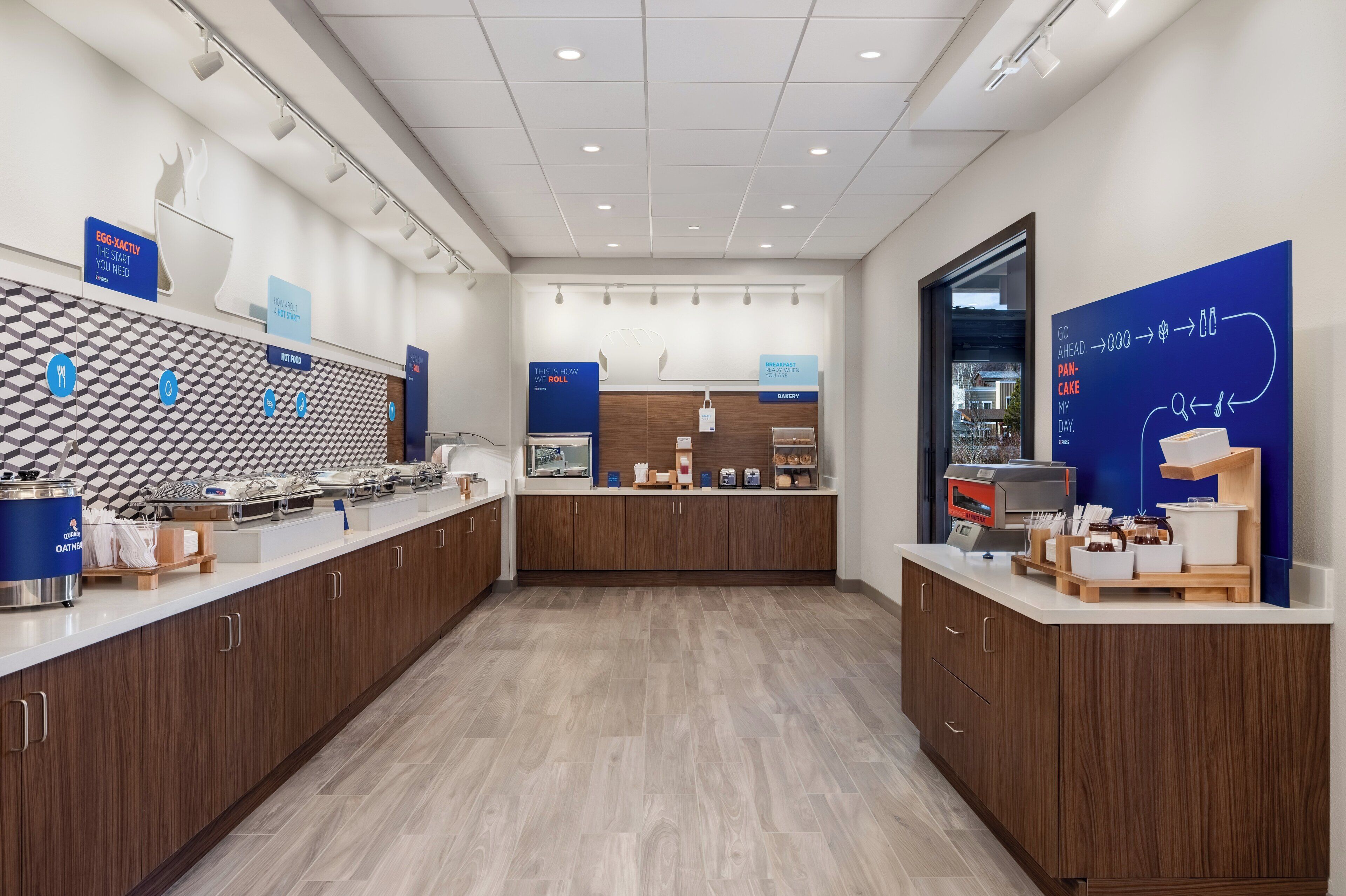 Un espace cuisine moderne doté d’un long comptoir, de divers appareils électroménagers et d’une enseigne bleue indiquant la section boulangerie.