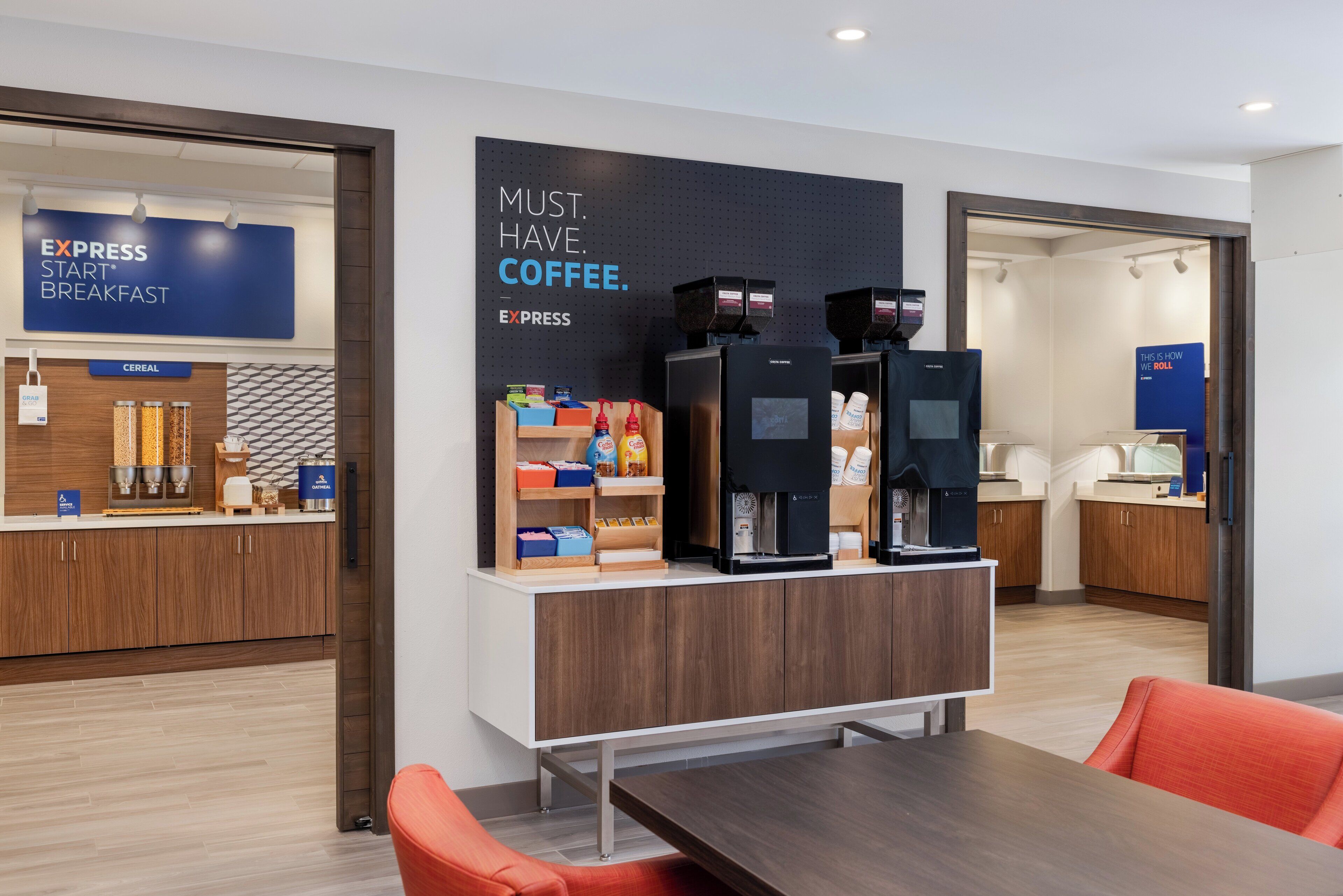 A modern kitchen area with a coffee station, cereal display, and a sign that reads "MUST. HAVE. COFFEE."
