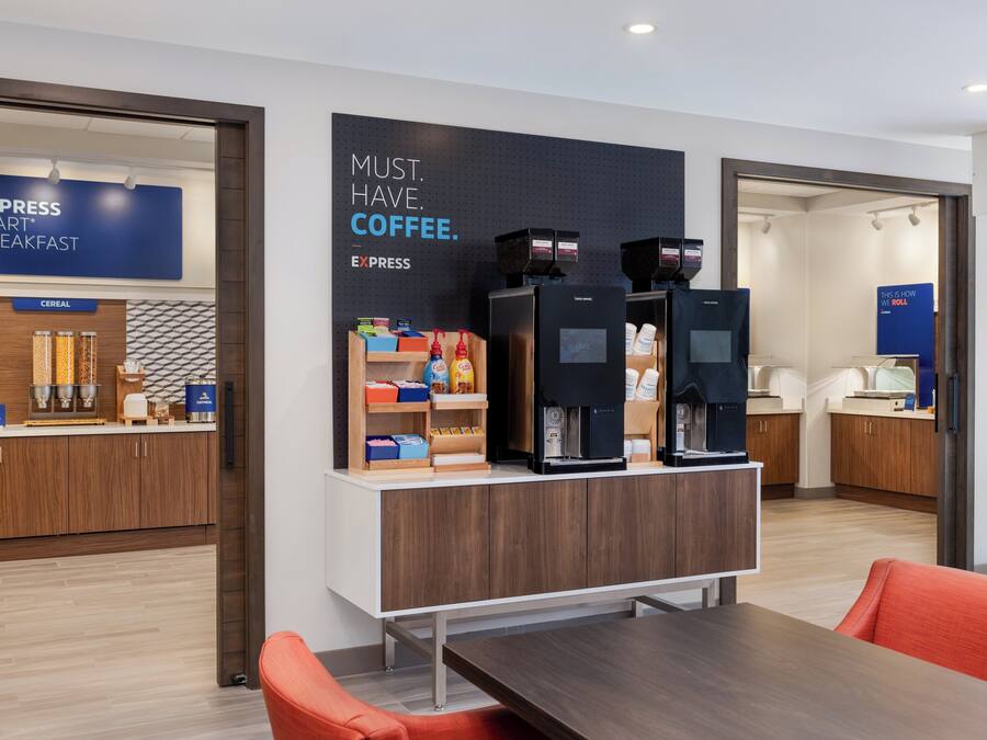 A modern kitchen area with a coffee station, cereal display, and a sign that reads "MUST. HAVE. COFFEE."