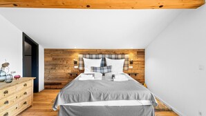 A bedroom with a wooden headboard, a bed with grey bedding, a wooden dresser, and a blue rug. - Cozy top floor studio with pool & sauna (Reit im Winkl)
