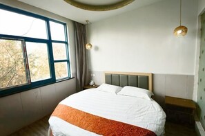 Une chambre à coucher comprenant un lit, une table de chevet, une fenêtre et un luminaire fixé au mur.