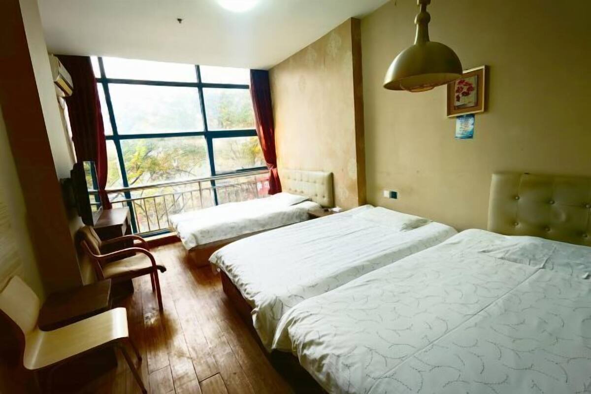 A room with two beds, a desk, and a window with a view.