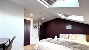 Ein Schlafzimmer mit Bett, Schreibtisch und Kleiderschrank. Über dem Bett befindet sich ein Dachfenster.