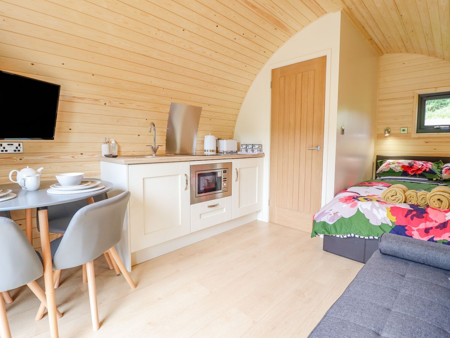 A compact room with a kitchenette, a dining area, and a bed.
