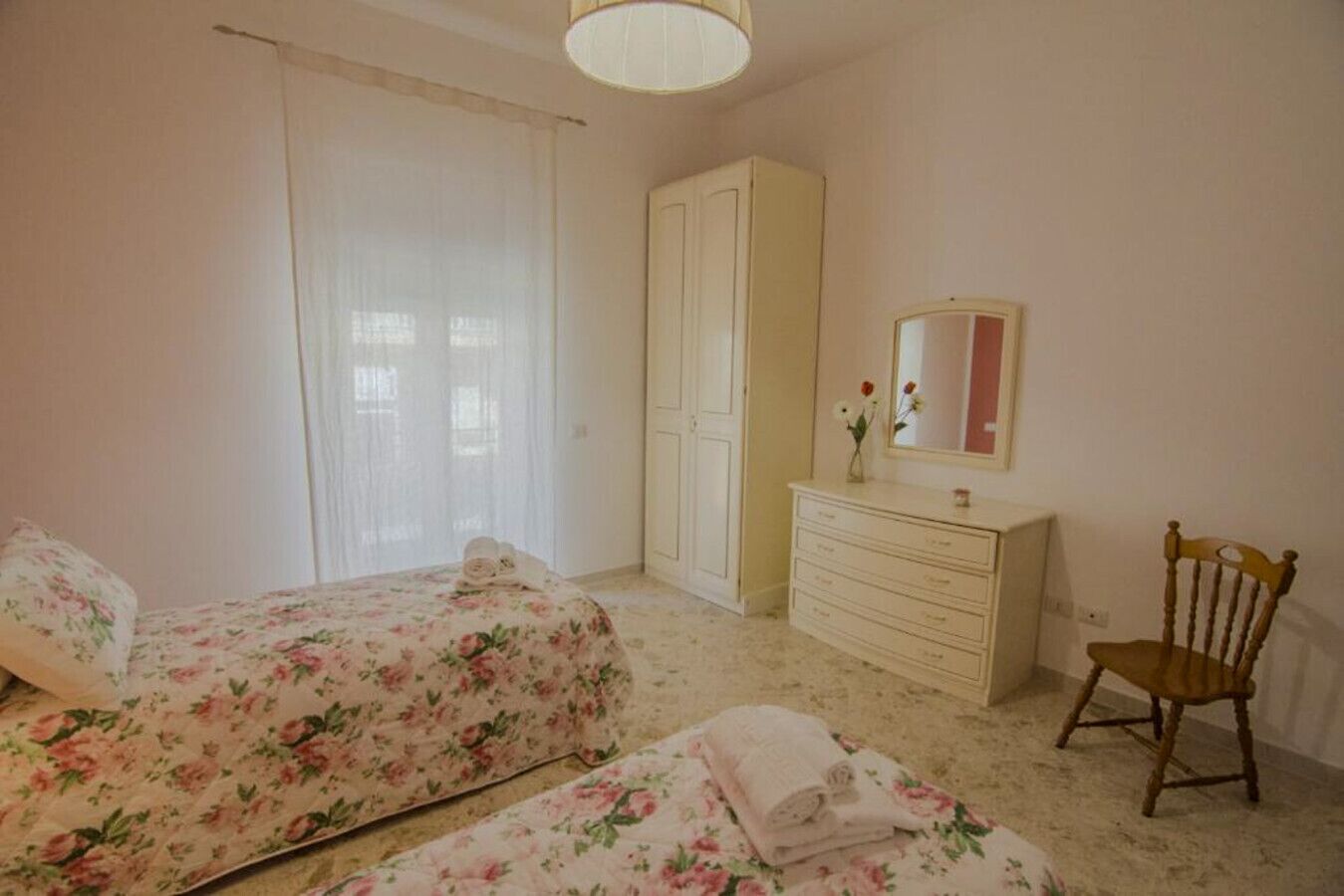 A bedroom with two beds, a dresser, a chair, and a mirror.
