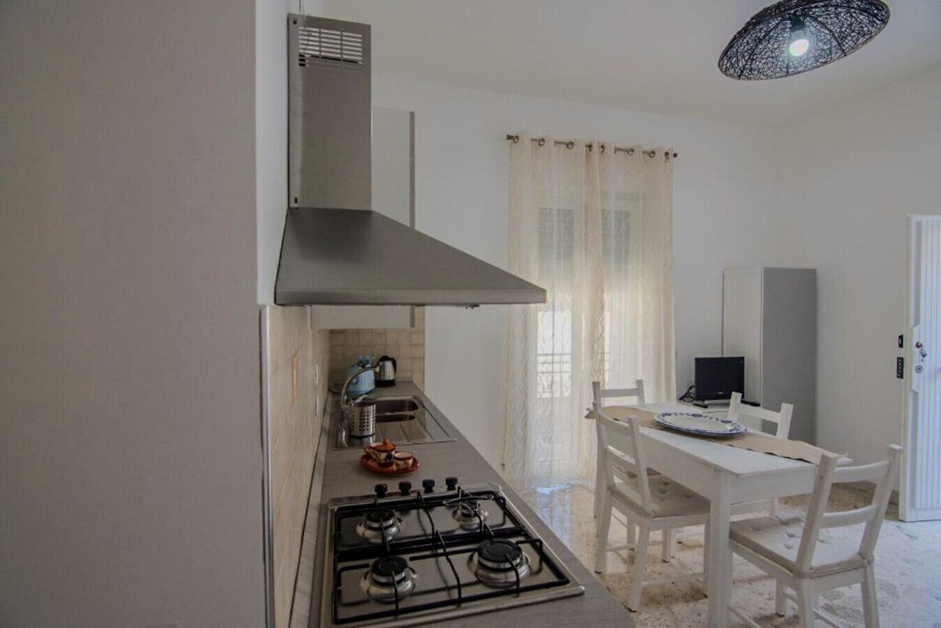 A compact kitchen with a gas stove, a small sink, and a dining area with a table and chairs.