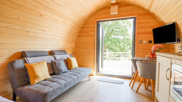 A cozy, wooden-paneled room with a sofa, a desk, and a television. - Eirlys (Dolgellau)