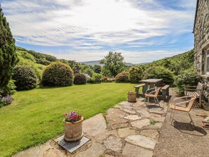 A stone patio with outdoor seating, a grassy lawn, and a stone wall. - Dwynant (Dolgellau)