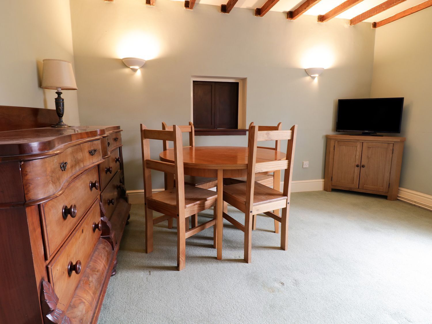 A room with a wooden dining table and chairs, a dresser, a television, and a cabinet.