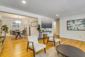 A modern living room with a dining area, wooden flooring, and contemporary furniture.