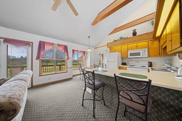A modern kitchen with a bar area, wooden cabinets, and a large window.