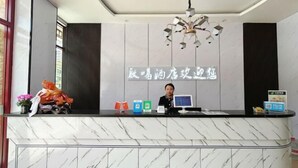 Un comptoir d’accueil d’hôtel avec un revêtement en marbre, un écran numérique et un panneau affichant des caractères chinois.