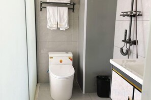 Un baño pequeño con inodoro, un bote de basura y un perchero para toallas.