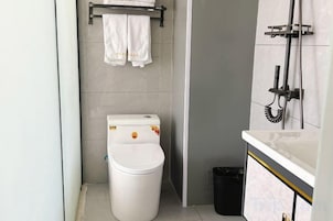 A compact bathroom with a toilet, a trash bin, and a towel rack.