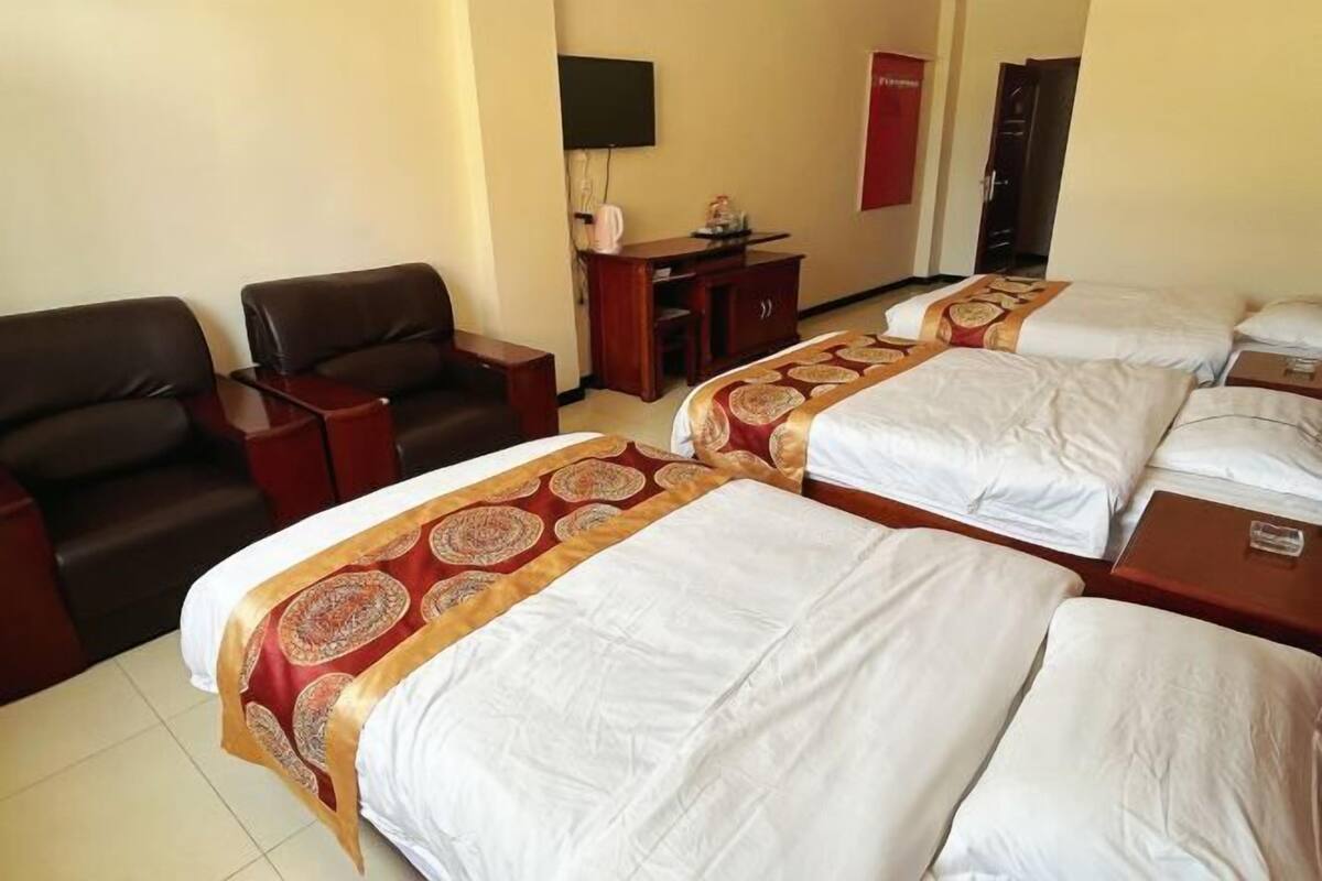 A hotel room with two beds, a desk, a chair, a TV, and a wardrobe.