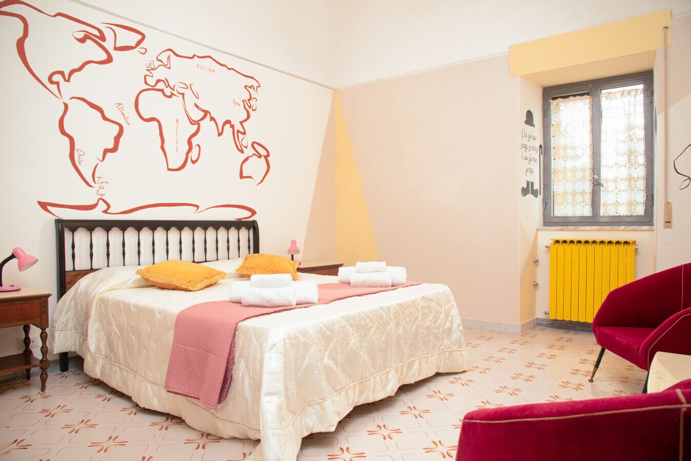 Une chambre à coucher avec un lit, une carte du monde accrochée au mur, une fenêtre avec des rideaux, un radiateur et un fauteuil rouge.