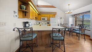 Une cuisine dotée de meubles en bois, d’un four à micro-ondes, d’un réfrigérateur et d’un coin repas avec des chaises et une table.