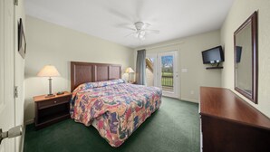 Une chambre d’hôtel avec un lit, un ventilateur de plafond, une télévision et une vue sur l’extérieur.