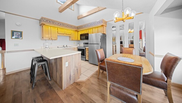Une cuisine moderne avec des meubles en bois, un îlot central et un coin repas doté de chaises en cuir.