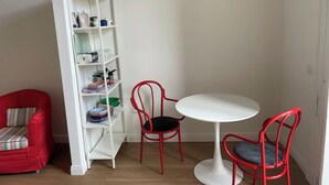 A room with a white bookshelf, two red chairs, a white table, and a red sofa. - The Romantic Apartment for two (Naples)