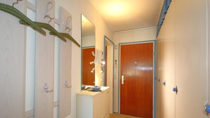 A hallway with a wooden door, a mirror, a small sink, and a patterned rug. - House Captain Christiansen 53 (Westerland)