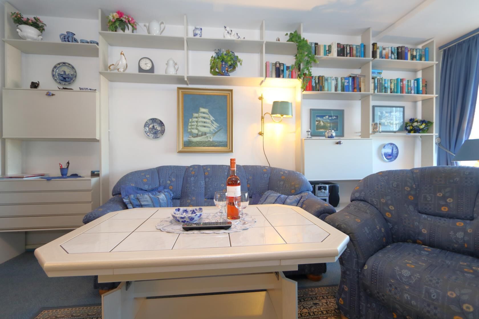 A living room with a sofa, a coffee table, and a bookshelf filled with books and decorative items.