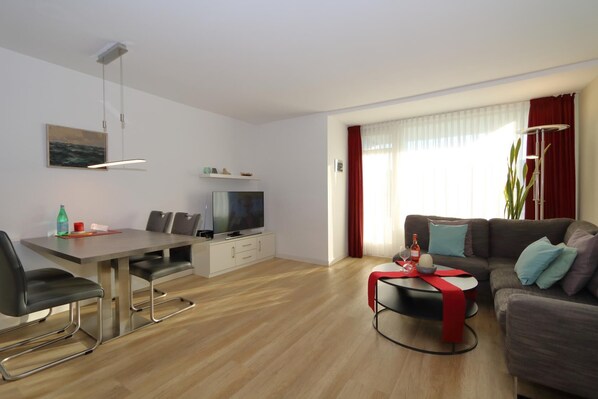 Een moderne woonkamer met een eethoek, een flatscreen televisie, een bank en een salontafel.