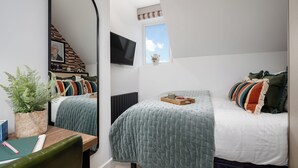 A bedroom with a bed, a desk, a mirror, a television, and a window. - Camden | Room B2 - Studio Apartment, Sleeps 2 (London)