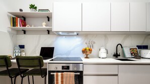 A modern kitchen with a built-in oven, a coffee maker, and a bowl of fruit on the counter. - Camden | Studio W Separate Kitchen (London)