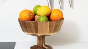 A kitchen with a marble countertop, a wooden bowl with fruits, and two knives mounted on the wall. - Camden | Studio W Separate Kitchen (London)