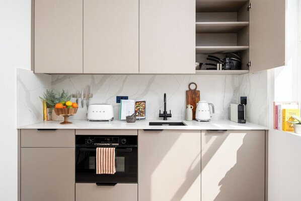 Una cocina moderna con horno empotrado, cafetera y tostadora.