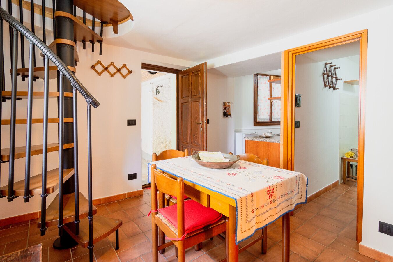 Un espace repas comprenant une table en bois, des chaises et un escalier en colimaçon.