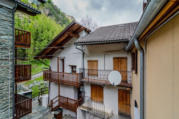 A traditional chalet with multiple balconies, stone walls, and a mountainous backdrop.