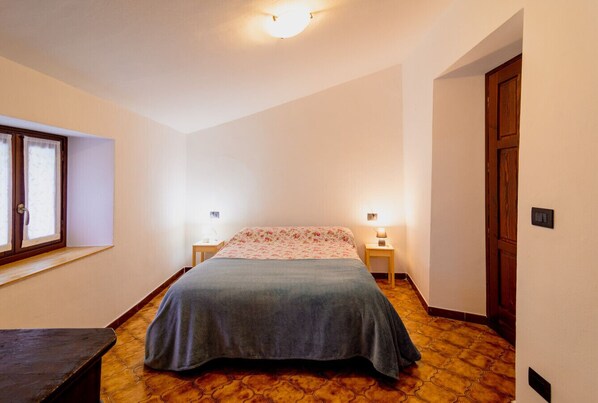 Une chambre à coucher avec un lit, des tables de chevet, une fenêtre et une porte.