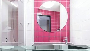 A bathroom with a glass shower enclosure, a round mirror, and a sink with a black countertop. - B&B HOTEL München City-Nord (Munich)
