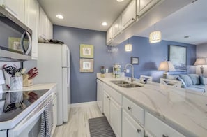 A modern kitchen with white cabinets, a marble countertop, and a built-in oven.