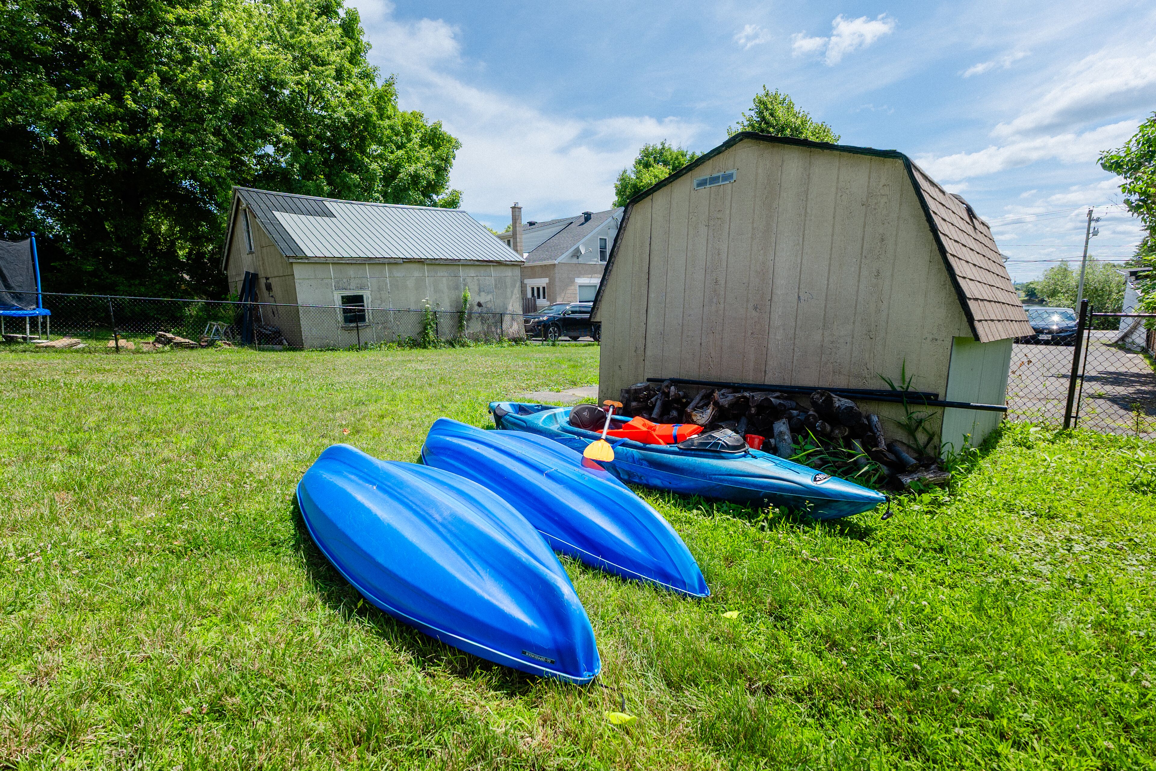 A grassy area with several blue kayaks and a shed.