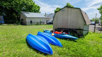 A grassy area with several blue kayaks and a shed.