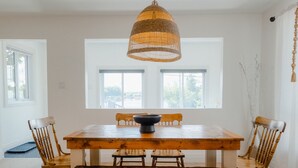 A dining area with a wooden table, four chairs, a bench, and a woven pendant light. - Cozy Lakeview Home with Water Access (Cornwall)