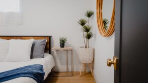 A bedroom with a bed, bedside table, potted plants, a mirror, and a door. - Cozy Lakeview Home with Water Access (Cornwall)