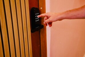 Une main appuyant sur un pavé numérique situé sur un verrou de porte.
