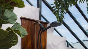 A wooden door with a shower hose attached to it, set against a white wall with a metal structure above. - Compact Bunk Room in Arts District + Free Parking (San Juan)